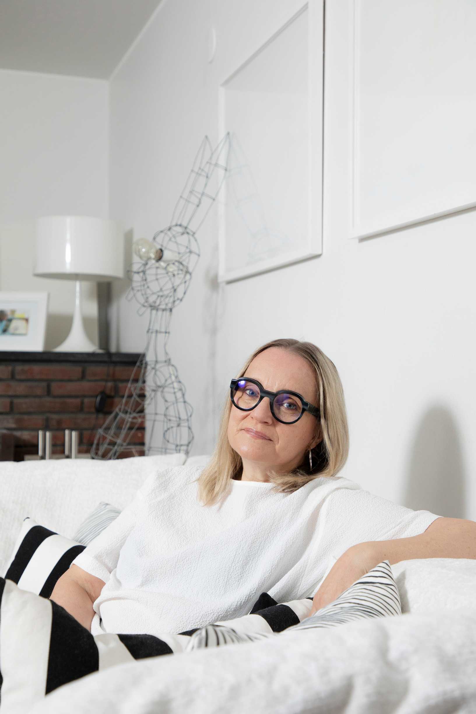 Helena Hietanen istuu valkoisella sohvalla