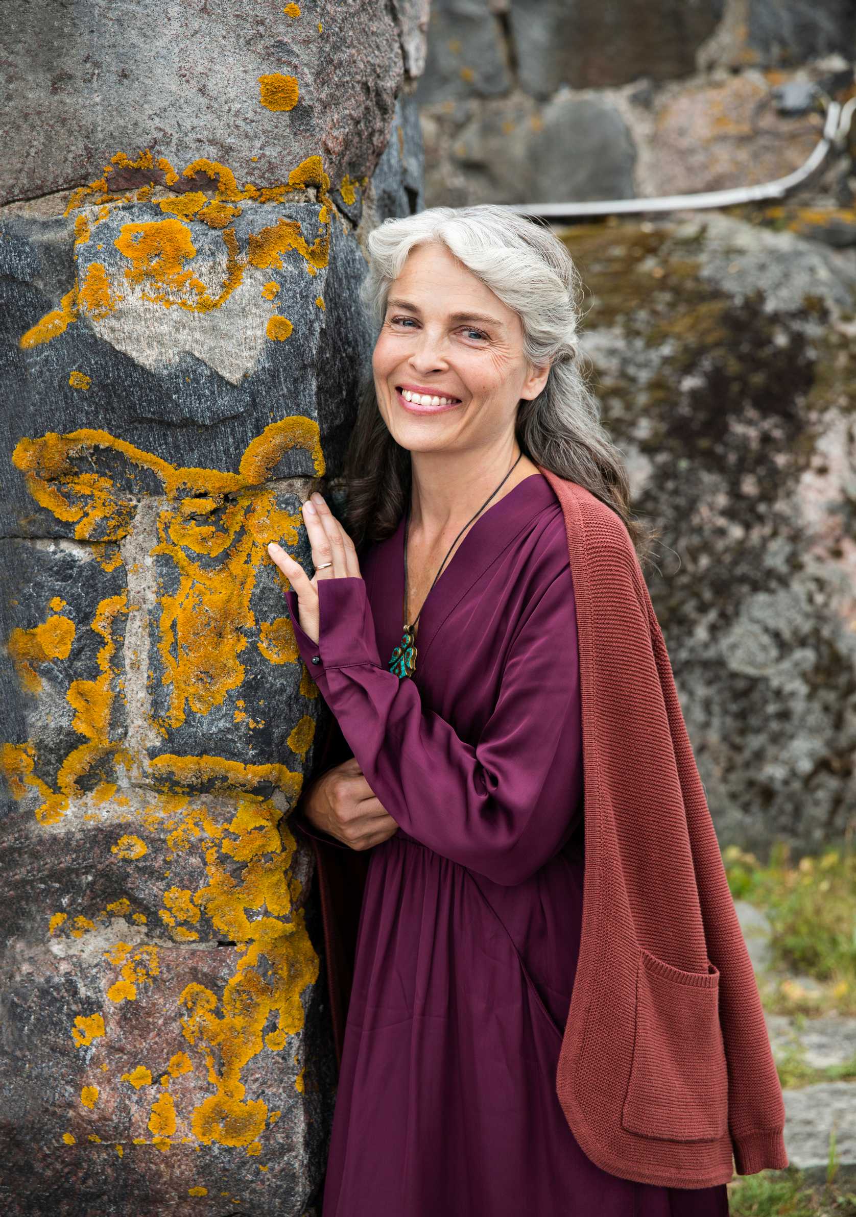 Irina Björklund hymyilee kallioon nojaten