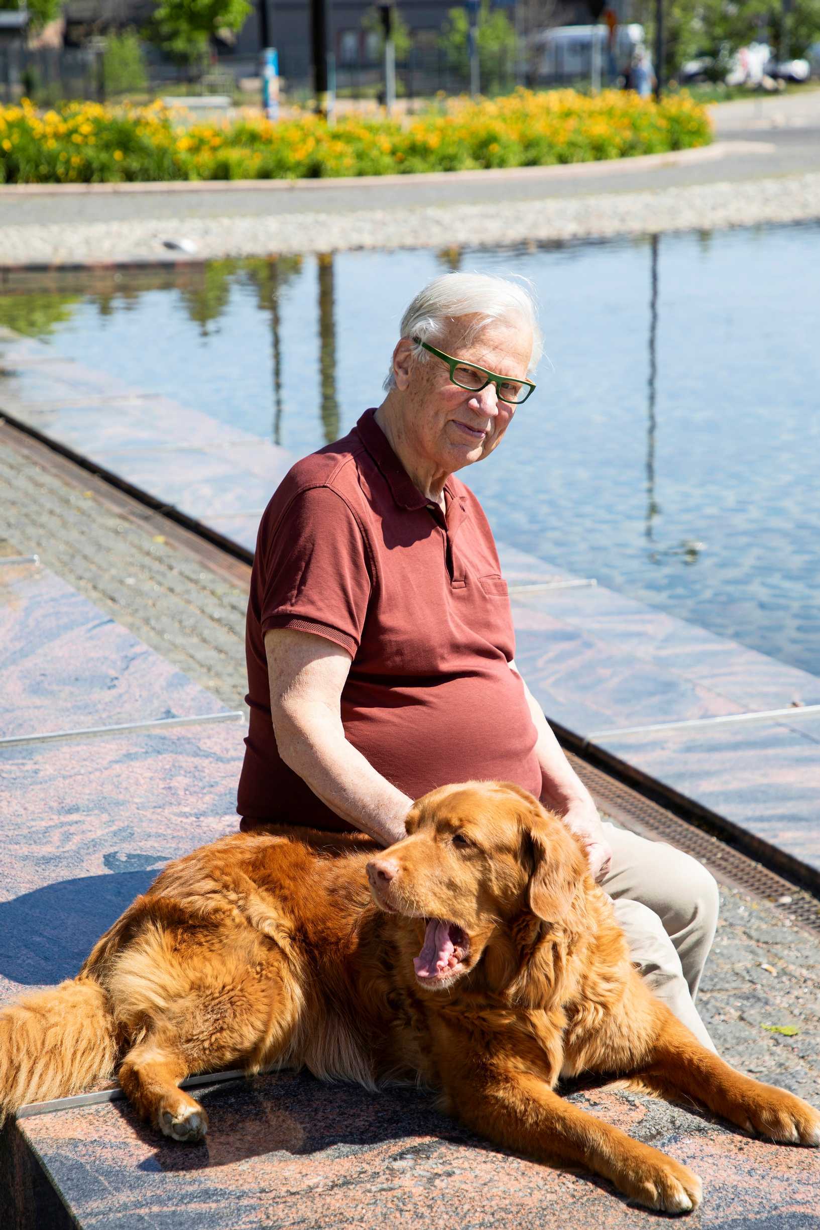 Wenzel Hagelstam istuu koiransa kanssa meren ääressä kivipenkillä.